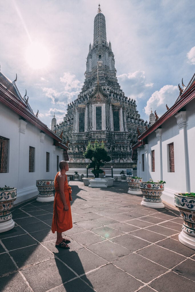 A monk stands in front of Wat Arun Temple